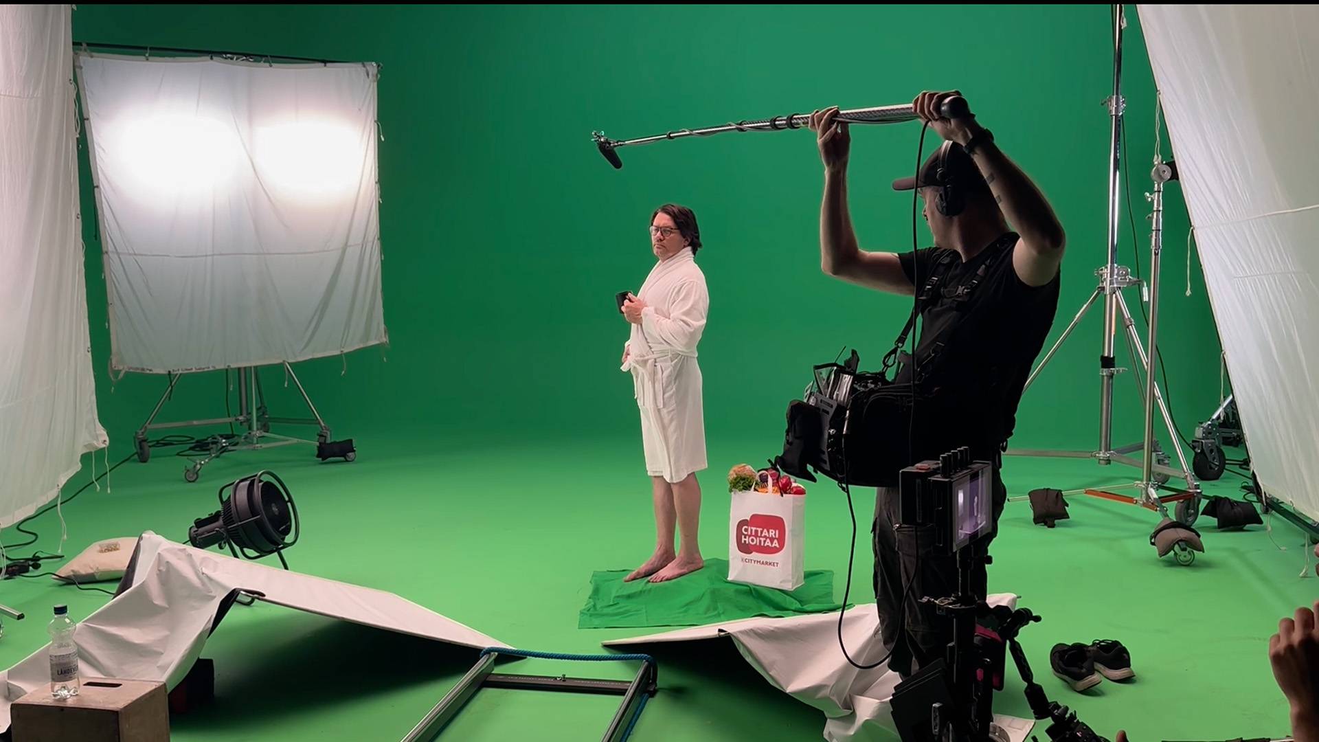Behind the scenes of a K-Citymarket commercial shoot, man standing in front of a green screen, being shot by film crew